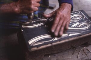 Nenek Tulian carving a panel.